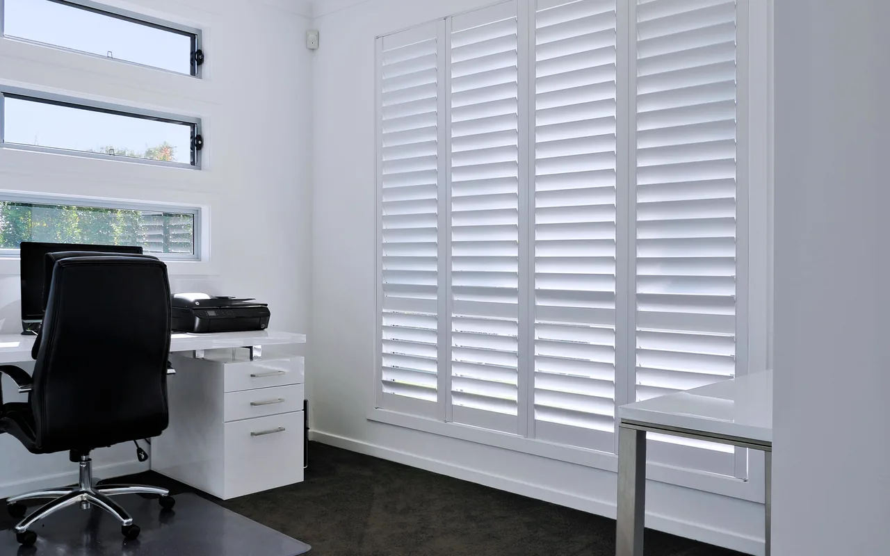White plantation shutters filling a bright Brisbane home office