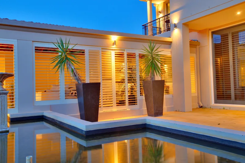 Aluminium shutters shading a poolside outdoor living area