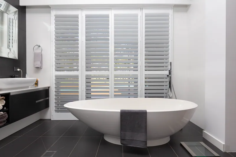Thermalite shutters behind a freestanding bath, showing their use in a wet area