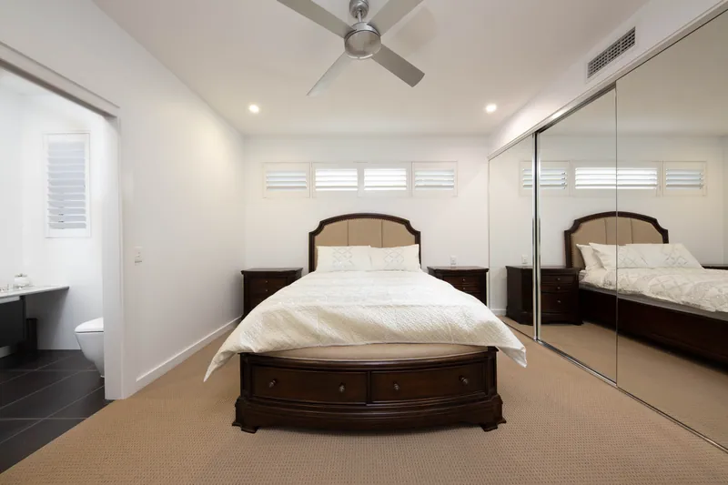 Bedroom with shutters at the window and mirrored robes opposite