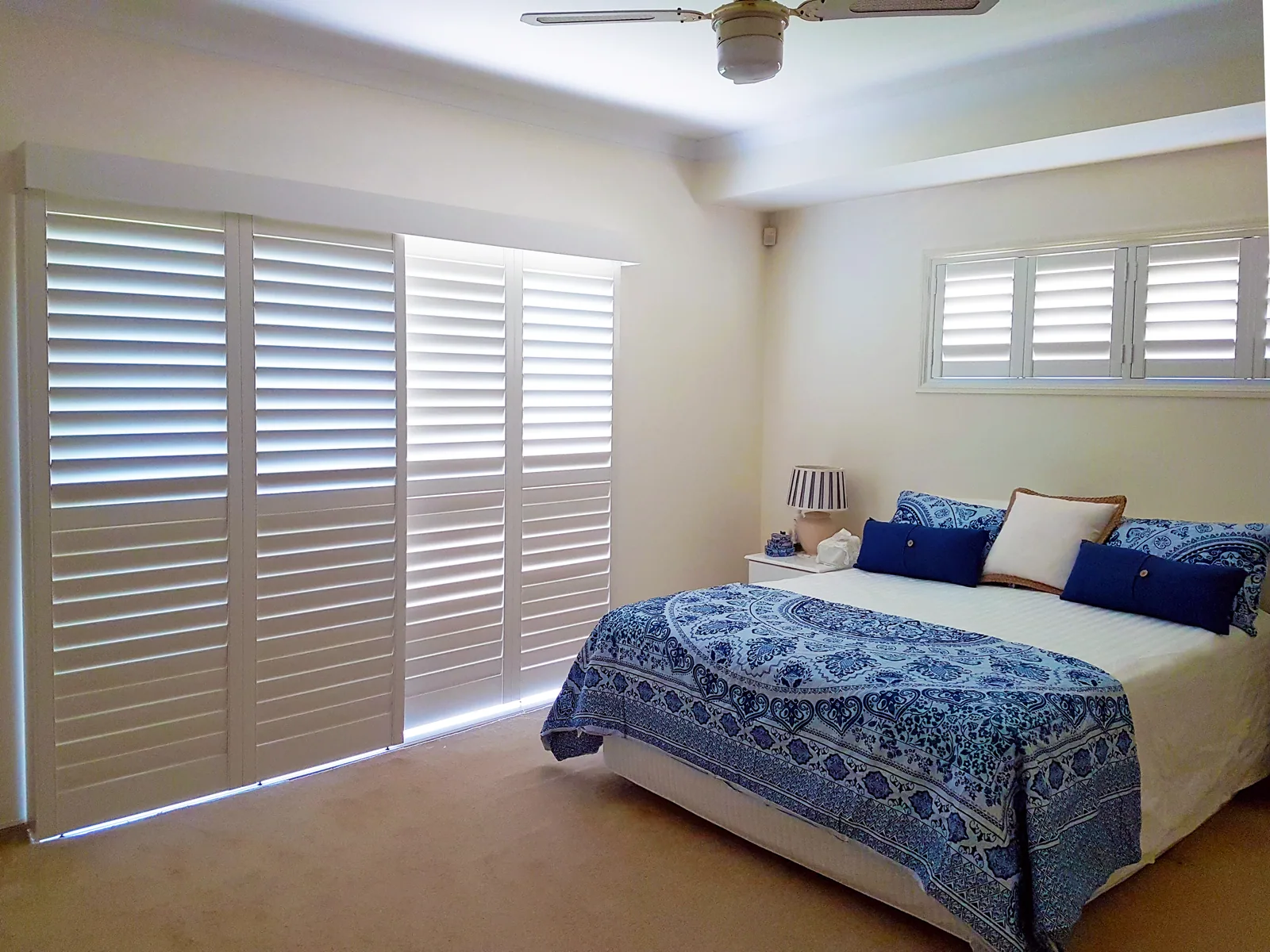 Sliding plantation shutters across a bedroom doorway with a matching window shutter