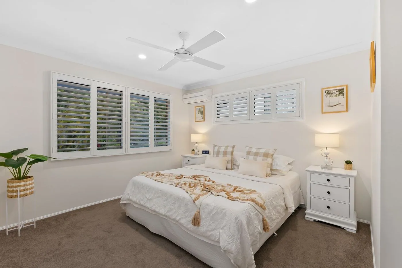 Plantation shutters on twin bedroom windows either side of the bed