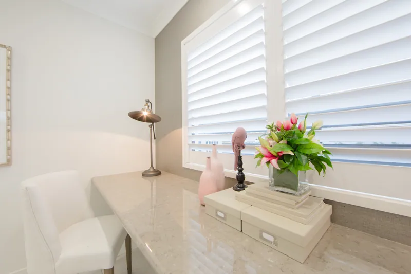 Plantation shutters across a dining room bay window, closed to soften afternoon light