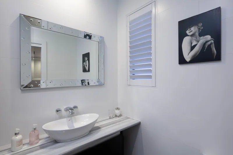 Ensuite vanity with a shuttered window above, privacy without losing daylight