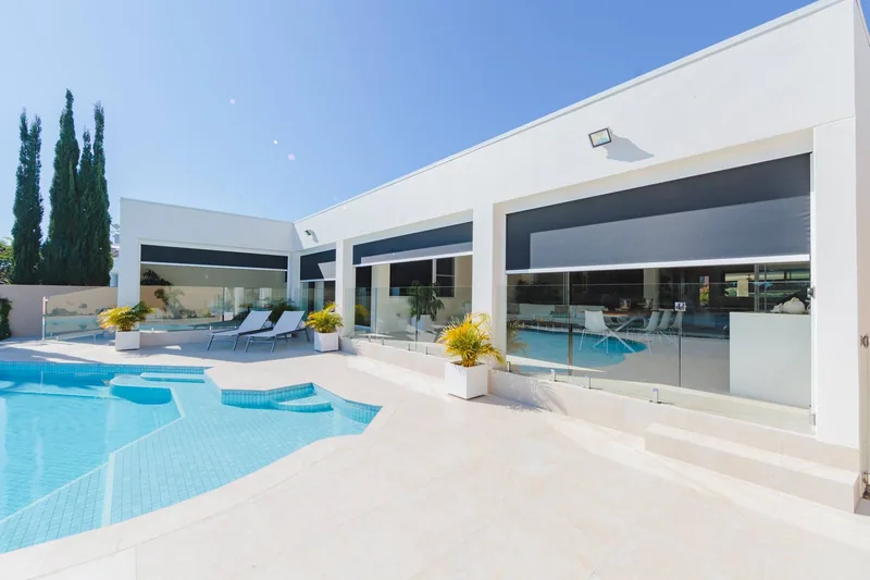 Outdoor screens across the rear of a home beside a swimming pool