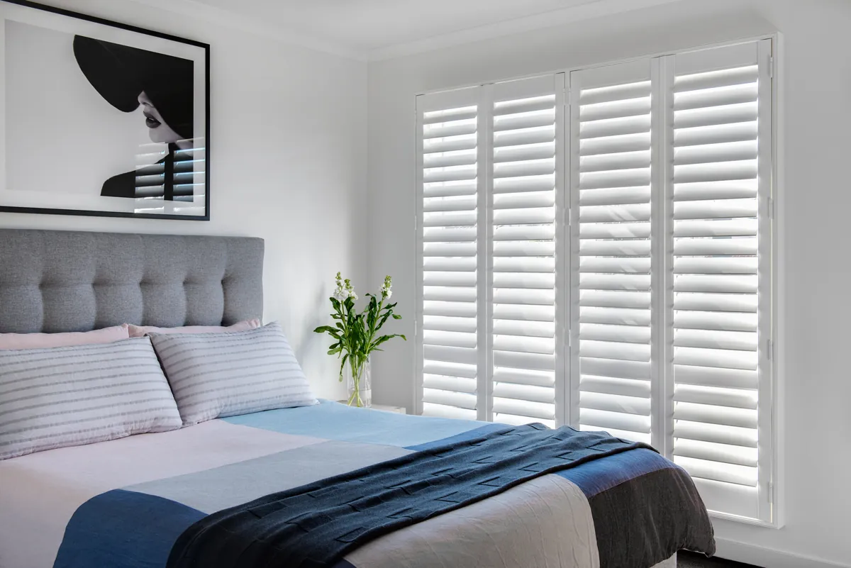 Bedroom fitted with white plantation shutters