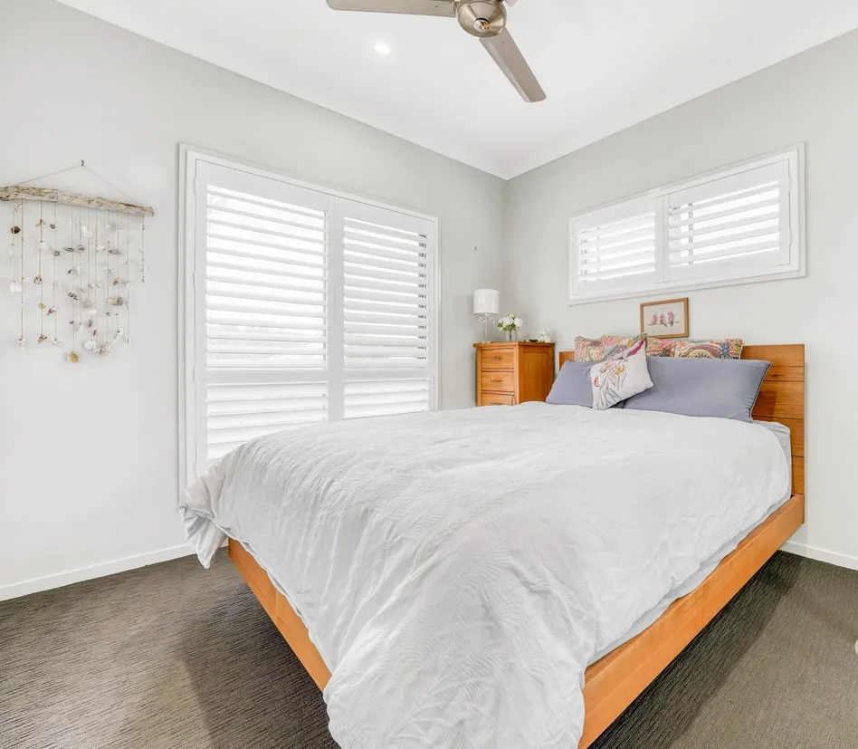 White Thermalite plantation shutters framing a large living-room window