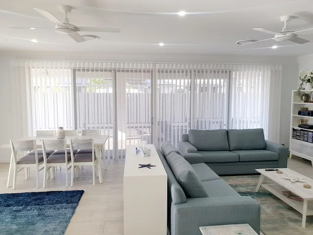 Veri Shades open to filter daylight behind a grey sofa and dining table